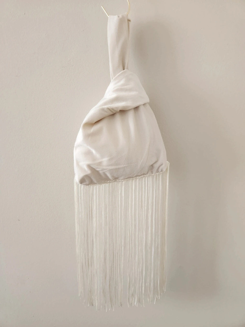 Japanese knot wrist bag in cream with a fringe trim