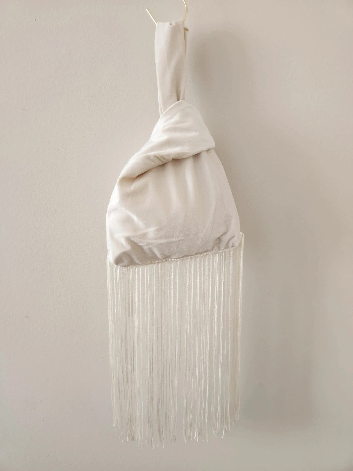 Japanese knot wrist bag in cream with a fringe trim