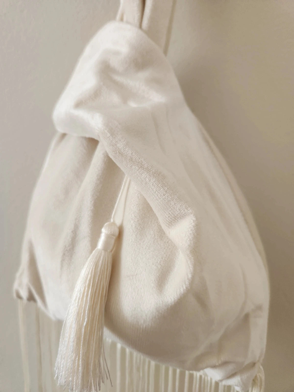 Japanese knot wrist bag in cream with a fringe trim