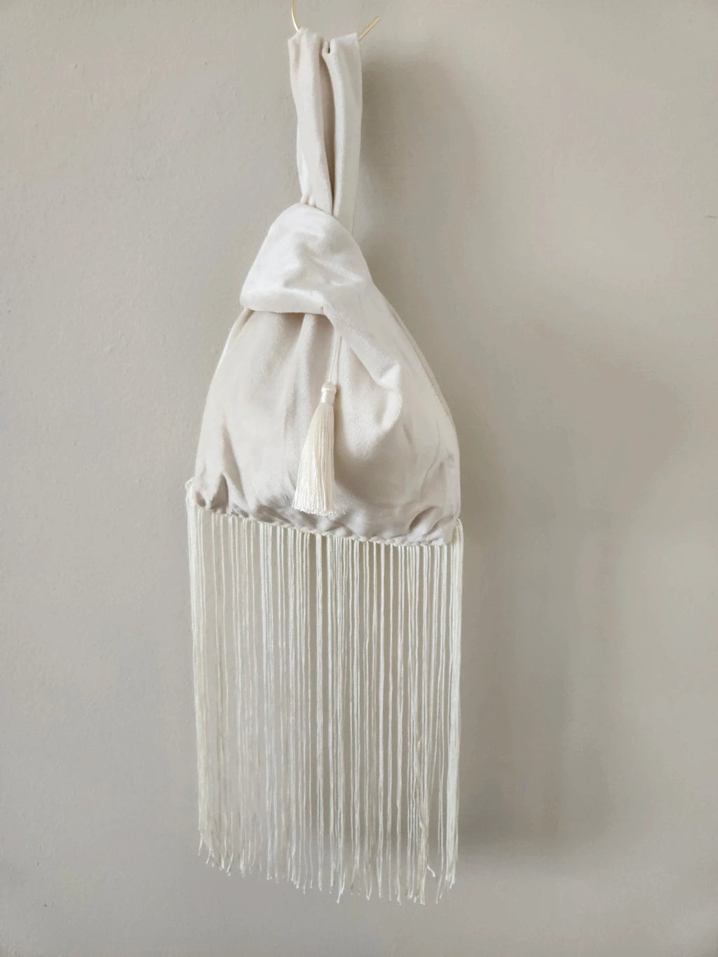 Japanese knot wrist bag in cream with a fringe trim