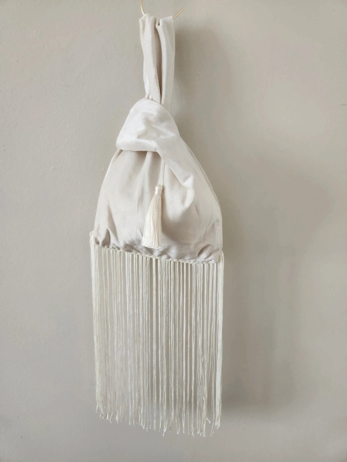 Japanese knot wrist bag in cream with a fringe trim