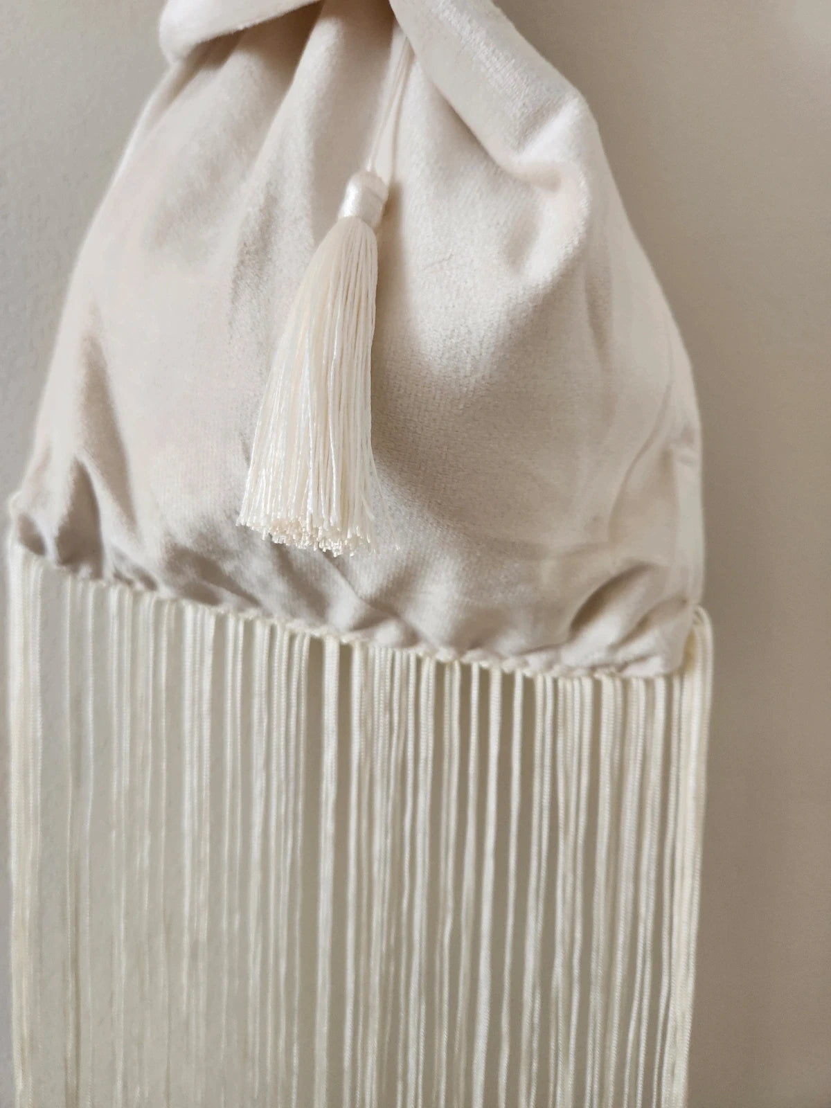 Japanese knot wrist bag in cream with a fringe trim