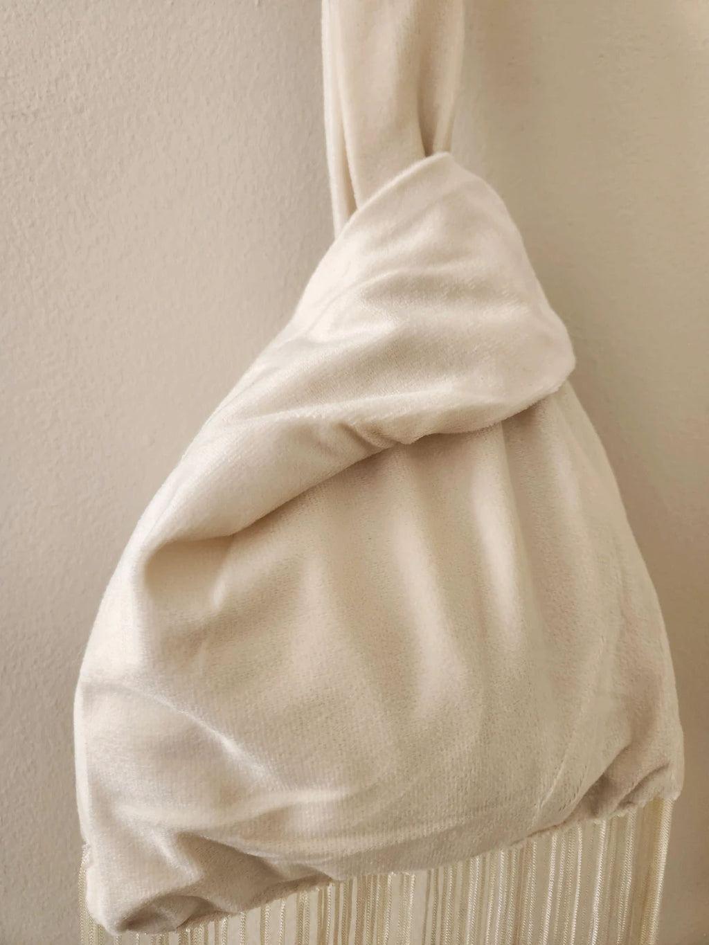 Japanese knot wrist bag in cream with a fringe trim